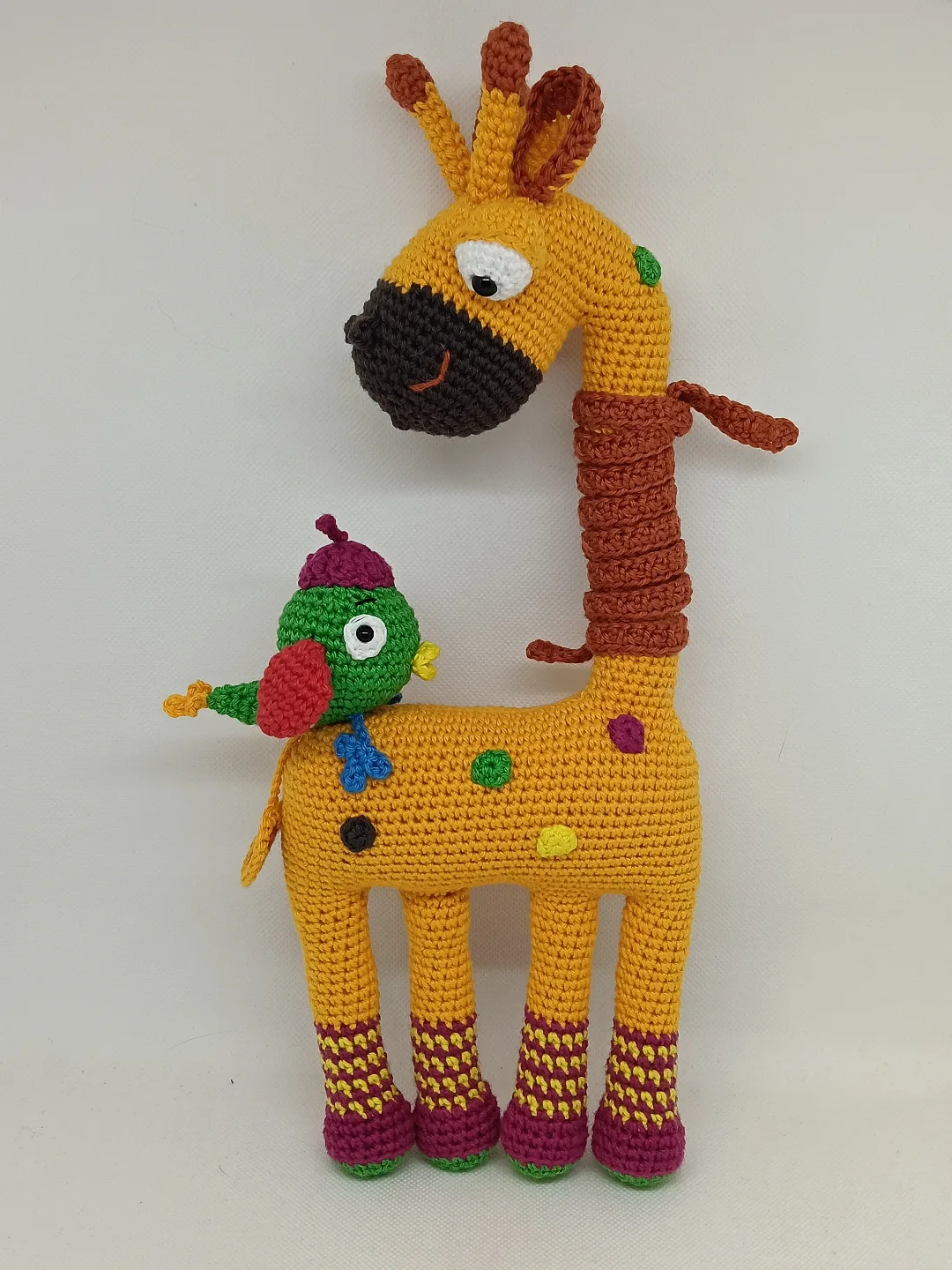 Jirafa amigurumi de colores con simpático pajarito